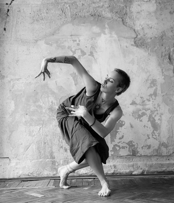 Woman in a calm, dynamic pose against a minimalist background, embodying fluid movement.